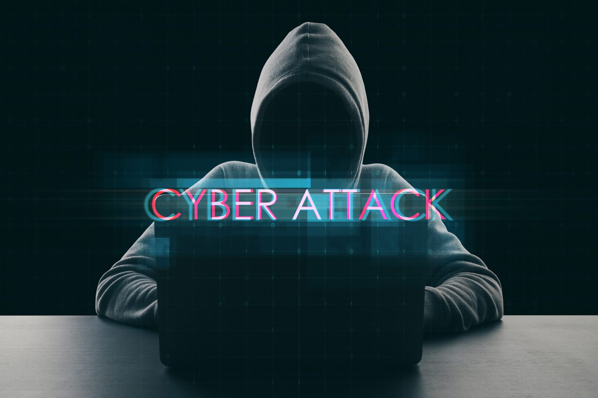 A hacker in a hoodie using a laptop with the words 